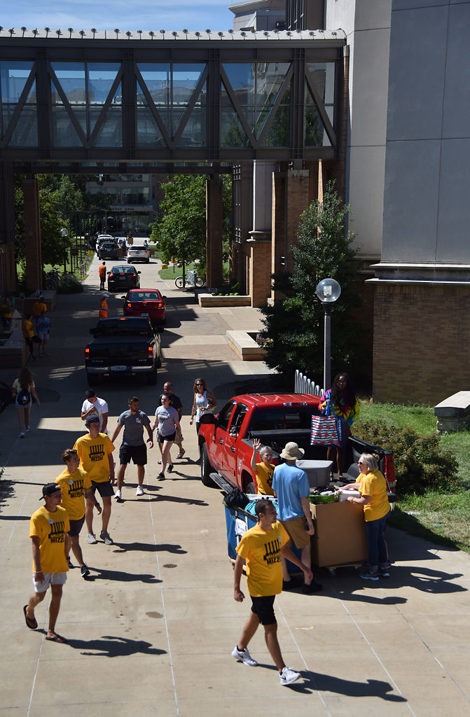 Volunteers, resident advisers, parents and students walk around Respect Hall to load and move items into some of the values dorms